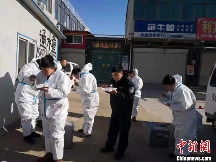 圖為藁城區(qū)增村鎮(zhèn)小果莊村疫情防控檢查站警員為暖和在陽光下吃飯?！堅露Y 攝