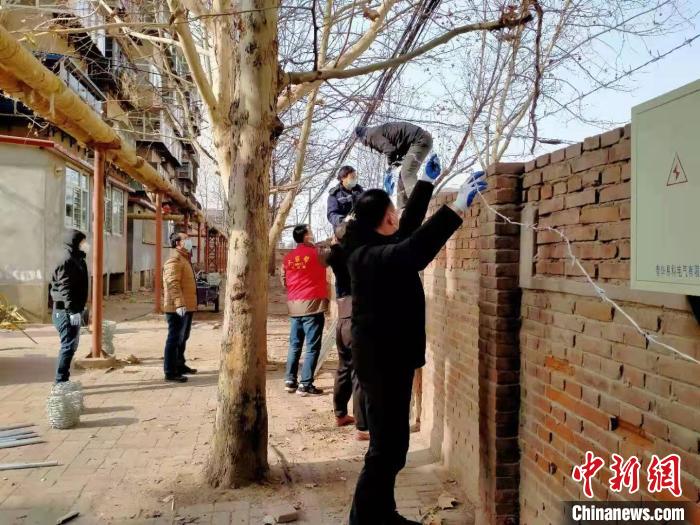圖為小區(qū)志愿者為小區(qū)圍墻加裝倒刺鐵網(wǎng)。　崔會(huì)芹 攝