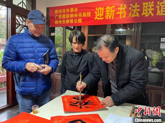 柳州市一書(shū)法家教兩位英國(guó)人書(shū)寫(xiě)春聯(lián)。　林馨 攝