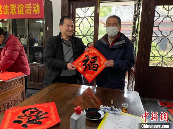 圖為一名日本人(右)展示其書(shū)寫(xiě)的春聯(lián)。　林馨 攝
