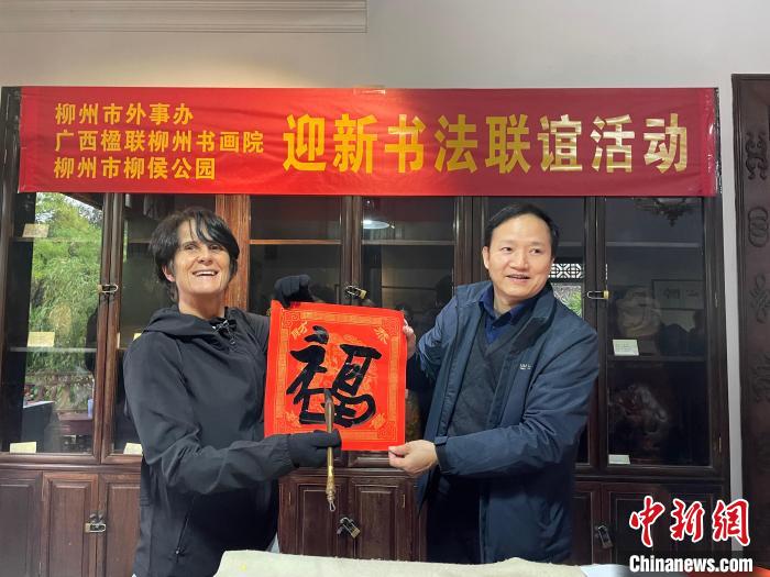 圖為一名英國(guó)人(左)展示其書(shū)寫(xiě)的春聯(lián)?！×周?攝