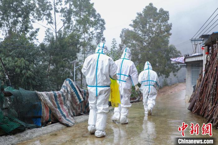 圖為在德保縣隆桑鎮(zhèn)果甫村，身著厚重防護服的歐秋潔和同伴步履蹣跚地行走。
