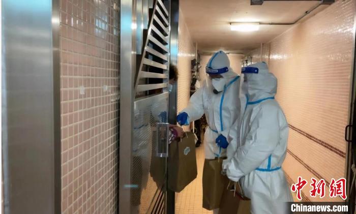 圖為吳學(xué)明和義工送抗疫物資到確診家庭手中?！∈茉L者供圖