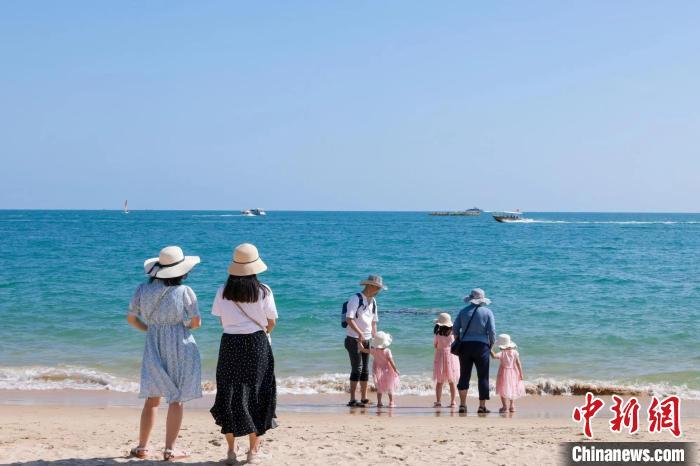 資料圖：家長帶著孩子在海邊嬉浪?！∮谓ㄐ?攝