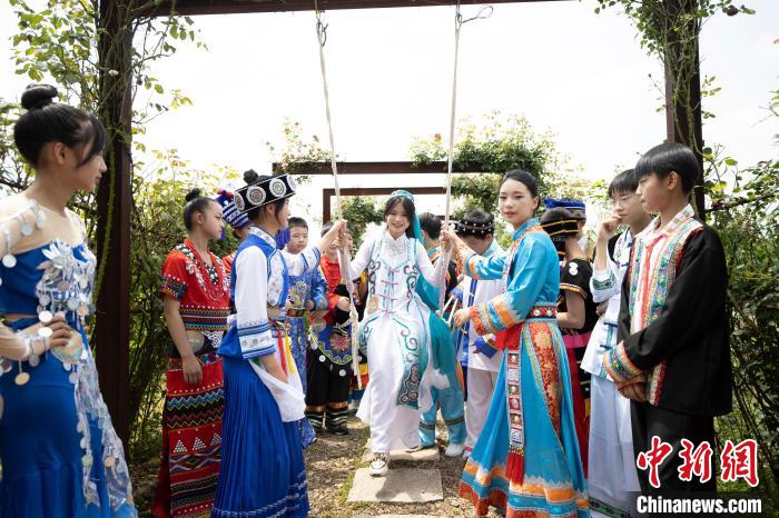 身著各民族傳統(tǒng)服飾的學生在玫瑰長廊蕩秋千 施紫楠 攝 攝