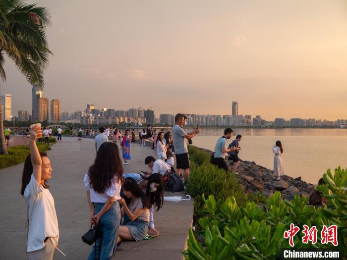 在海邊拍攝夕陽美景的游客?！×栝?攝