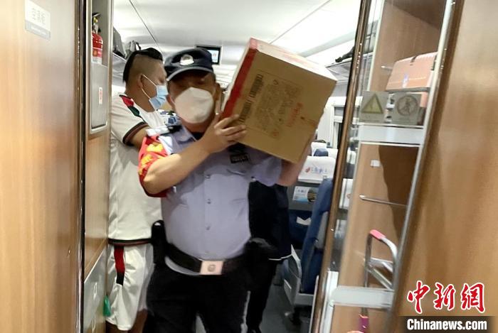 乘警扛著餅干等食物到車(chē)廂分發(fā)給旅客?！⌒熘蓁F路公安處供圖