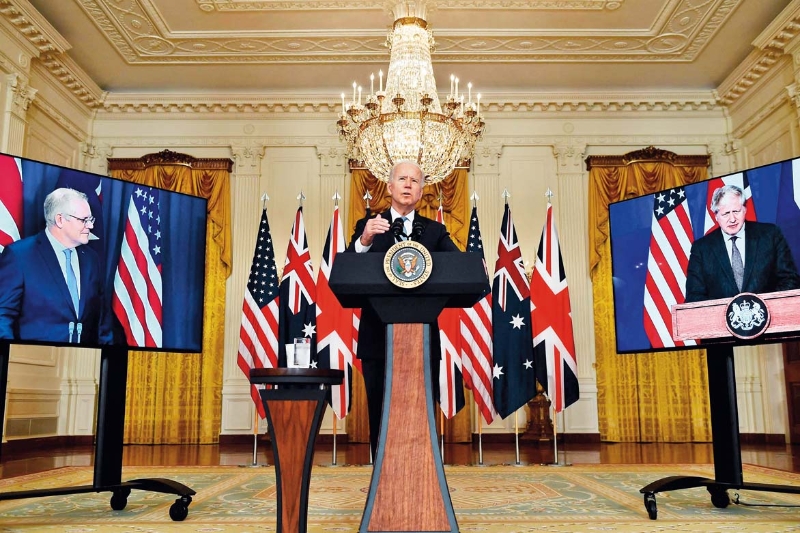 9月15日，美國總統(tǒng)拜登（中）在華盛頓白宮與英國首相約翰遜（右側(cè)屏幕中）和澳大利亞總理莫里森（左側(cè)屏幕中）舉行視頻會議
