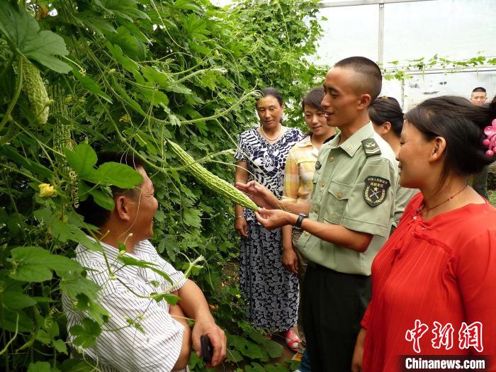 圖為官兵向民眾傳授蔬菜種植技術(shù)?！●R軍 攝