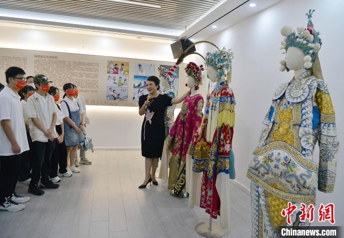 圖為福建省實(shí)驗(yàn)閩劇院工作人員為研學(xué)體驗(yàn)營(yíng)學(xué)生介紹閩劇戲服?！埍?攝