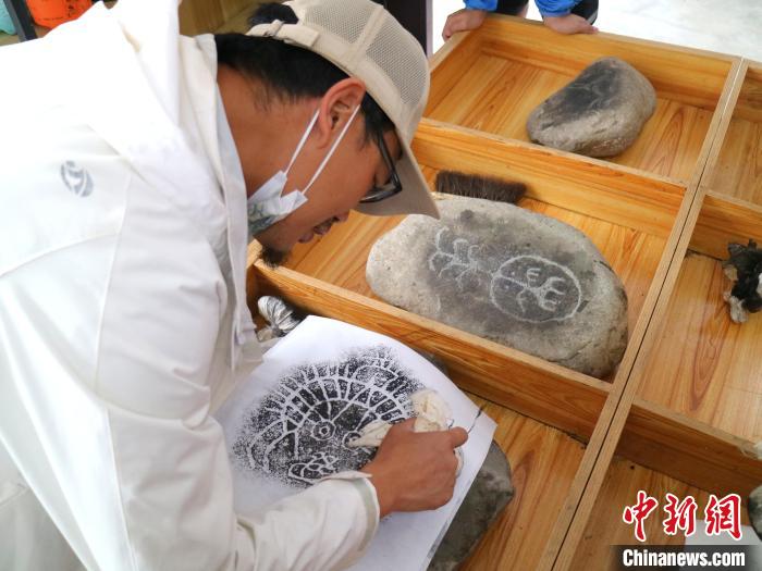 臺青用墨包為巖畫印記上色?！±钤?攝