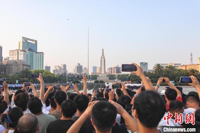 圖為不少市民在八一廣場(chǎng)上觀看升旗儀式?！⒘巍z