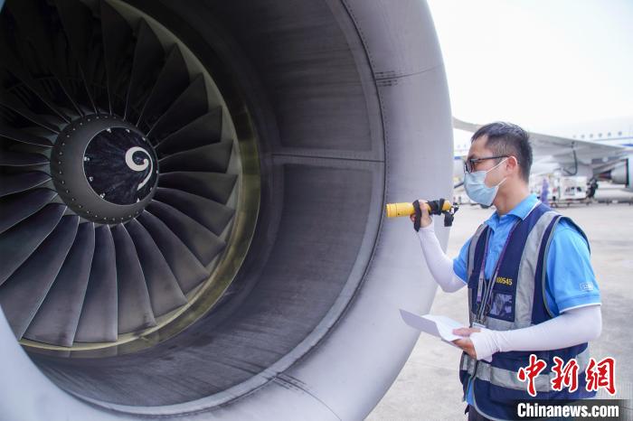 圖為航線維護工程師對飛機發(fā)動機進行檢查?！￡惞谘?攝