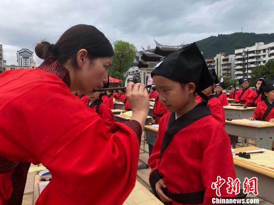 資料圖：在“點(diǎn)朱啟智”環(huán)節(jié)，先生在學(xué)童的額心點(diǎn)上朱砂，寓意孩子從此開啟智慧，目明心亮。曉東 攝