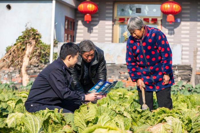 　江蘇省泰州市海陵區(qū)蘇陳派出所民警在蘇陳社區(qū)田間地頭向農(nóng)戶進(jìn)行普法宣傳(2021年12月4日攝)。新華社發(fā)(湯德宏 攝)