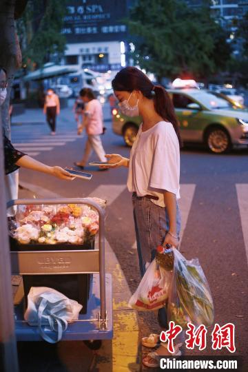 手提兩袋蔬菜的成都市民在選購鮮花。　受訪者供圖