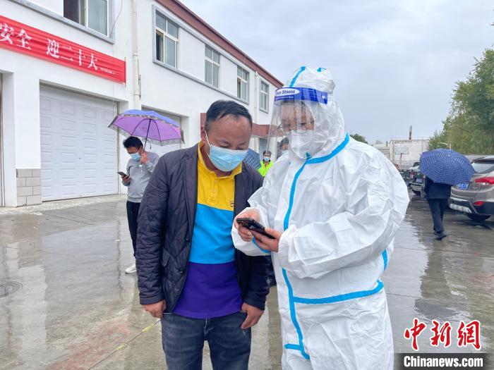 圖為王衛(wèi)玲(右)幫助做核酸的人員進(jìn)行個(gè)人信息登記?！≈煊例?攝