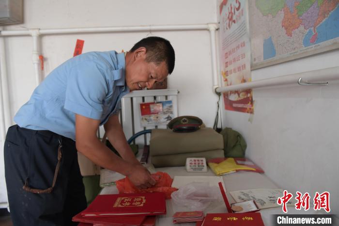 圖為謝建民整理當(dāng)兵時的榮譽證書?！『鷸|育 攝