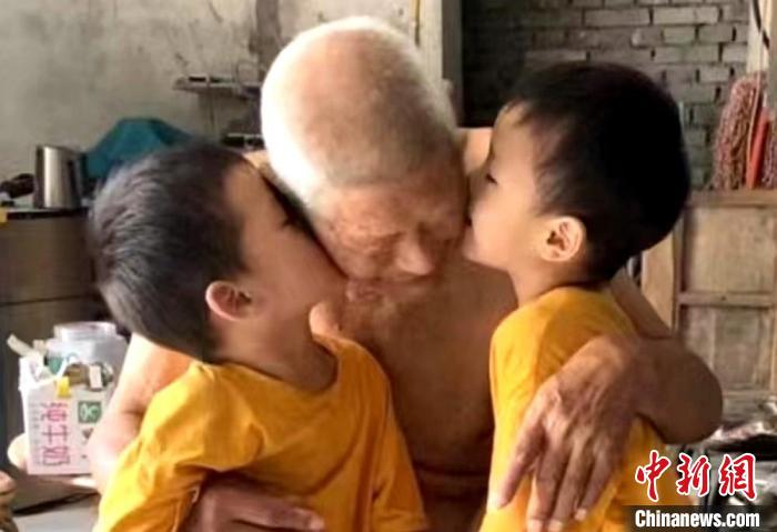 雙胞胎重孫依偎在太爺爺懷里，親吻太爺爺。　劉笑供圖