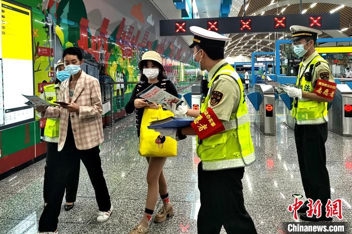 圖為交通執(zhí)法人員向出站旅客發(fā)放相關(guān)宣傳冊。　張旭 攝