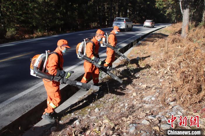 消防隊員利用風(fēng)力滅火機收攏國道旁可燃物?！⊥鯘蓷?攝
