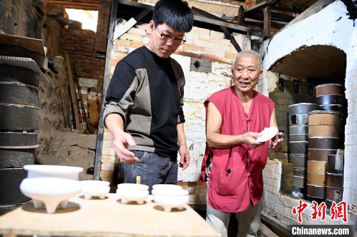在窯口，林俊徒弟把已上釉的素坯傳給師傅?！埥鸫?攝