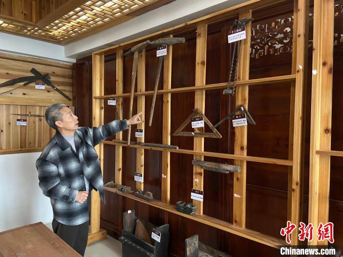 圖為葉偉平向前來參觀的民眾介紹修復(fù)古建筑時使用的工具?！⒂駶?攝