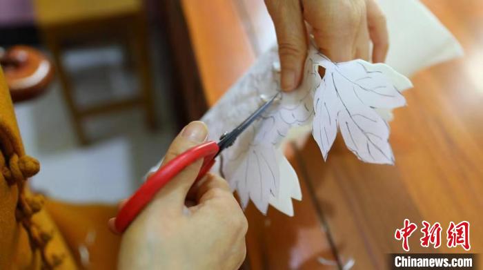 常鳳靈先用白色熟宣紙對(duì)照牡丹圖案裁剪成型，然后拼貼，再以工筆技法上色?！【抟翱h融媒體中心供圖