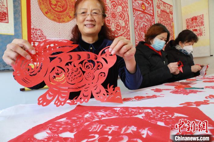 非遺傳承人董雙強(qiáng)在展示自己創(chuàng)作的剪紙作品?！±詈?攝