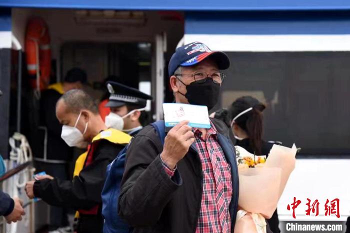 搭乘泉金航線的乘客展示手中的船票?！∪?攝