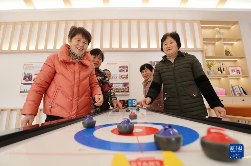 2月16日，在湖州市德清縣阜溪街道興山未來社區(qū)居家養(yǎng)老服務(wù)中心，社區(qū)老人在打“桌上冰壺球”。（圖源：新華社）