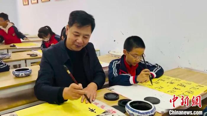 圖為“校長(zhǎng)爺爺”同學(xué)生們一起練書法?！￡惙?攝