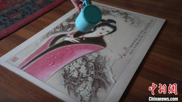 藺烈演示在板刻線畫作品上做防水試驗(yàn)，展示作品不僅防水還不掉色，濕水后還可用布擦拭?！∪诸?攝