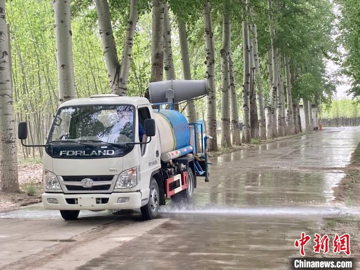 圖為灑水車在對(duì)地面進(jìn)行濕化，降低飄絮強(qiáng)度?！⌒戽?攝