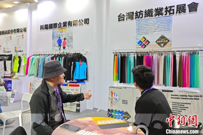 臺商邱鶴銘(左)在展位上介紹新研發(fā)的功能面料?！枪跇?biāo) 攝