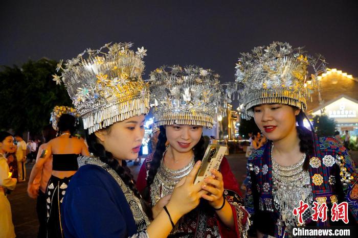圖為身著苗族服飾的游客正在翻看照片。　韋國政 攝