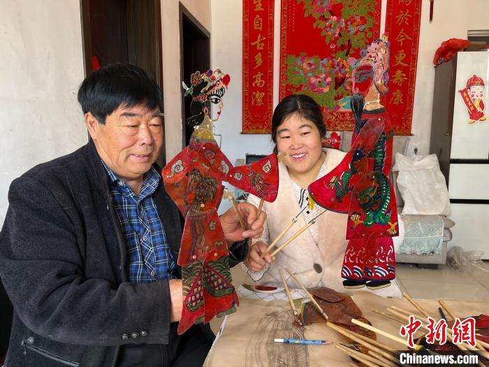 圖為馮克獻和女兒展示制作完成的皮影道具?！●R瑾 攝