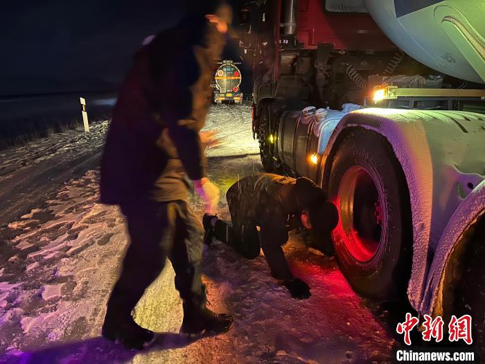 圖為民警幫助受困車輛安裝防滑鏈。　果洛州委宣傳部供圖