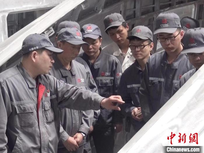 周晶輝正在為徒弟們講解司機(jī)室前窗框平度控制。　受訪者供圖