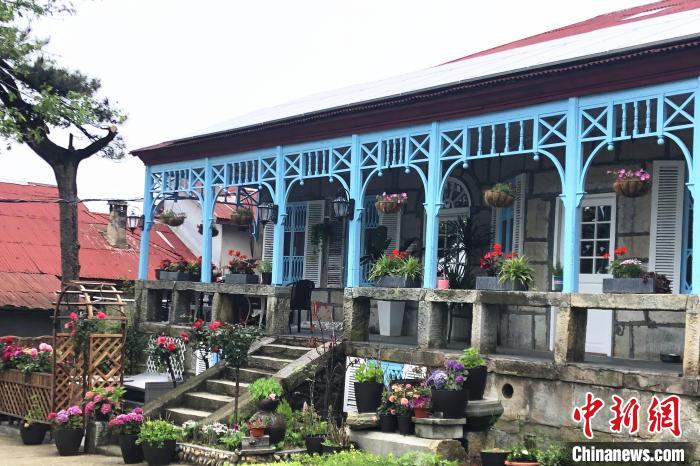 走進(jìn)喬尼·約翰遜在廬山上租住的別墅，藍(lán)色敞開(kāi)式外廊，一排石條凳上平均間隔的木頭柱支撐著拱券?！蛆i泉 攝