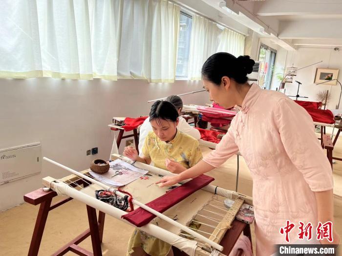 圖為陶衛(wèi)華正在指導(dǎo)繡坊的繡娘刺繡?！±铐嵑?攝