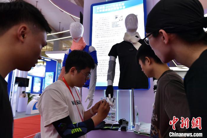 圖為參觀者在展會上體驗具有人體健康監(jiān)護預警功能的衣服?！埍?攝