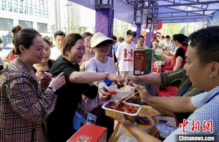 圖為江西南昌英雄城啤酒龍蝦燒烤節(jié)上，游客爭(zhēng)相品嘗鐵河小龍蝦預(yù)制菜?！⌒陆▍^(qū)融媒體中心供圖