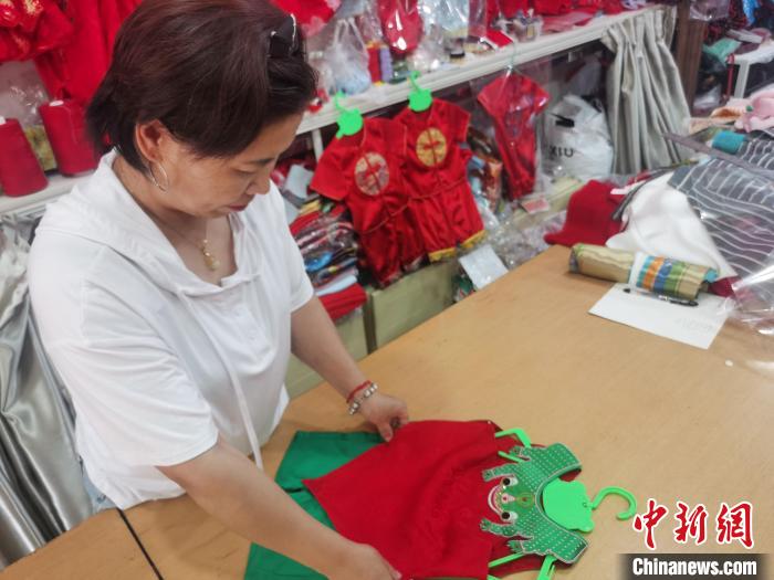 圖為勝芳古鎮(zhèn)一家兒童傳統(tǒng)服飾店，店員正在整理剛做好的青蛙衫?！⌒蟻喣?攝