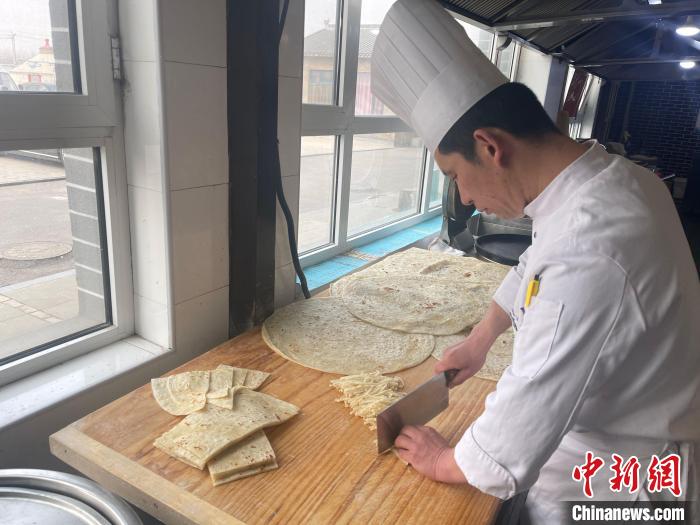 陳經(jīng)偉將餅切成長條備用。　楊靜 攝