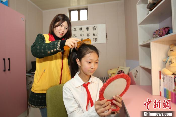 鄒城市“希望小屋”愛心媽媽志愿服務(wù)隊志愿者為兒童扎辮子?！⊥跹├?攝