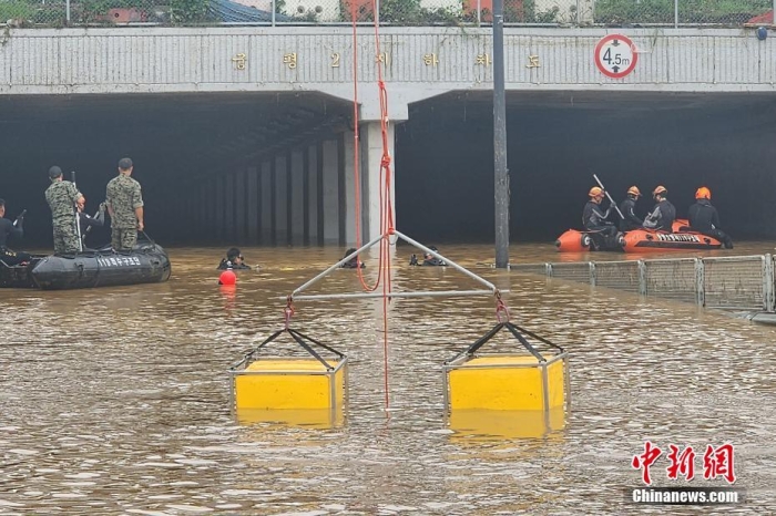 韓國(guó)救援人員沿著一條被洪水淹沒(méi)的道路搜尋失蹤人員，這條道路通往被洪水淹沒(méi)的地下隧道。視覺(jué)中國(guó)