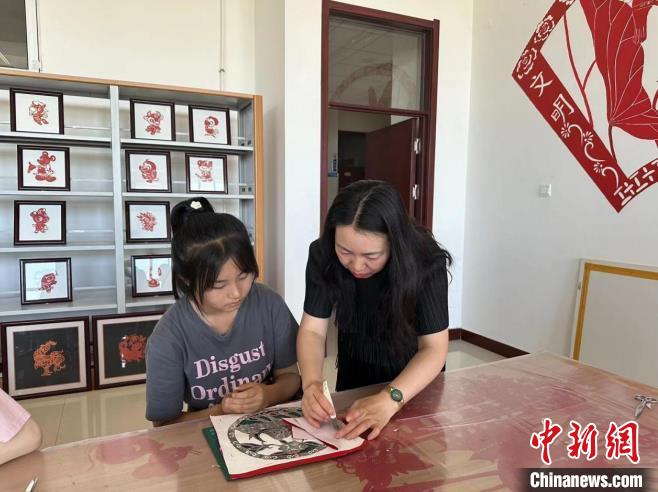 圖為胡穎指導(dǎo)學(xué)員學(xué)習(xí)剪紙藝術(shù)?！罹靶?攝