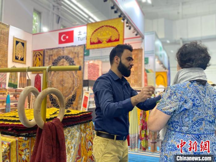 土耳其國(guó)家館工作人員向游客展示當(dāng)?shù)匚膭?chuàng)產(chǎn)品。中新社記者張瑋攝