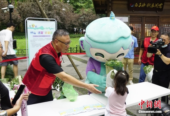 杭州亞運會吉祥物“琮琮”“宸宸”“蓮蓮”在浙江杭州西湖畔參加蓮蓬荷葉義賣活動，圖為亞運會吉祥物“蓮蓮”將分包好的蓮蓬、荷葉交給顧客。<a target='_blank' href='/'>中新社</a>發(fā) 王瓊苓 攝
